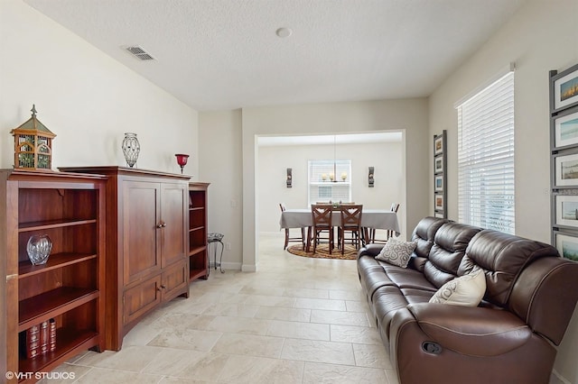 living area featuring visible vents, a textured ceiling, and baseboards