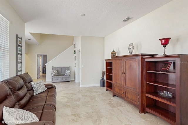 living area with baseboards, visible vents, and a textured ceiling