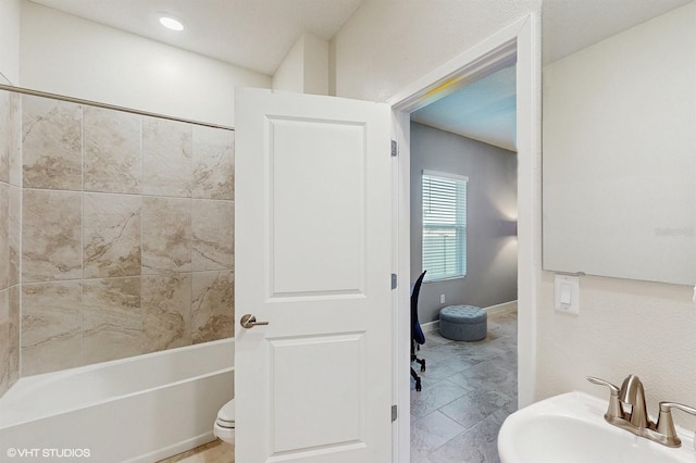 bathroom with tub / shower combination, a sink, and baseboards