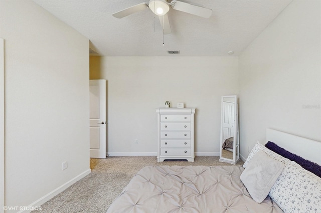 carpeted bedroom with baseboards, visible vents, ceiling fan, and a textured ceiling