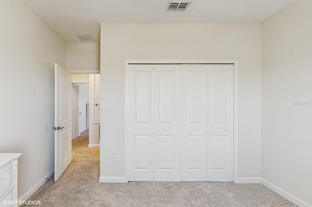 unfurnished bedroom with light carpet, baseboards, visible vents, and a closet