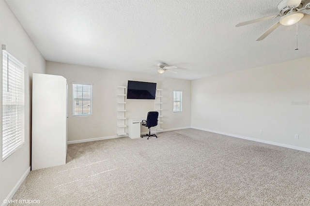 unfurnished living room featuring a ceiling fan, a healthy amount of sunlight, carpet flooring, and a textured ceiling