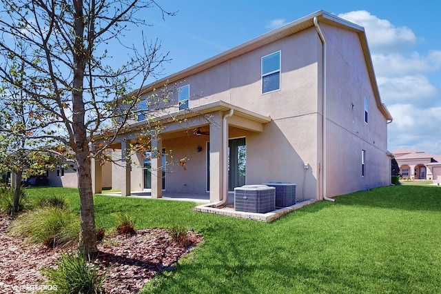 rear view of property featuring a ceiling fan, a patio, a yard, central AC, and stucco siding