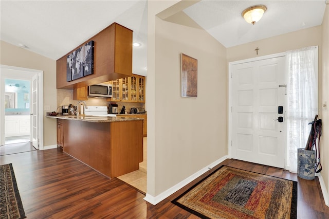 foyer featuring vaulted ceiling, wood finished floors, and baseboards