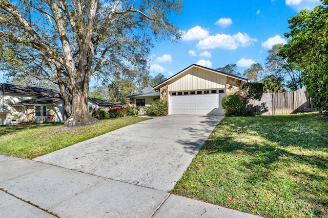 view of front facade with a garage, concrete driveway, a front lawn, and fence