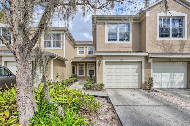 view of property with stucco siding, an attached garage, and concrete driveway