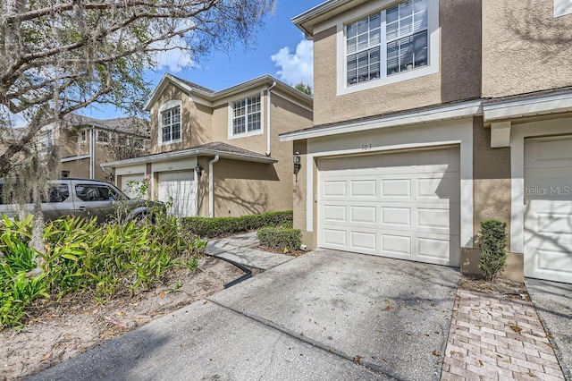 view of front facade featuring stucco siding, driveway, and a garage