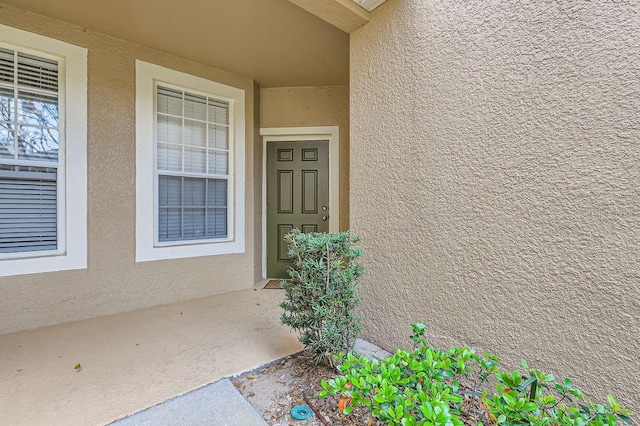 doorway to property featuring stucco siding