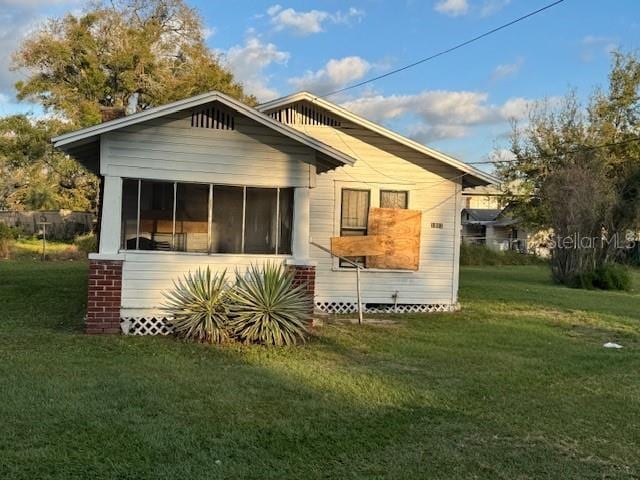 back of house with a sunroom and a lawn