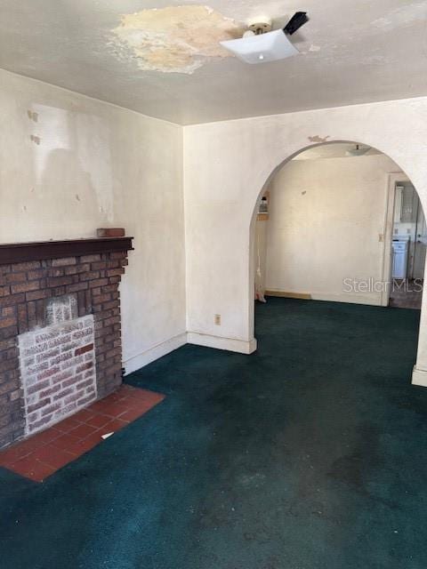 unfurnished living room featuring arched walkways, carpet, and baseboards