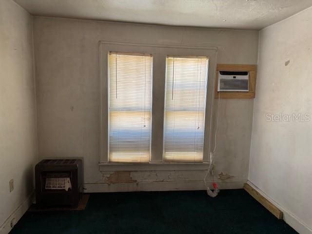 empty room featuring baseboards, heating unit, and a wall mounted AC