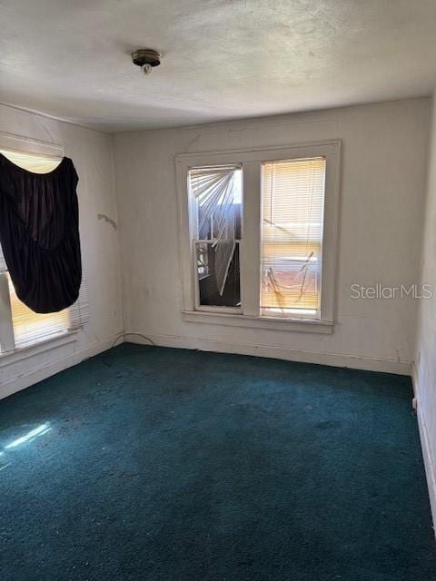 carpeted spare room featuring baseboards