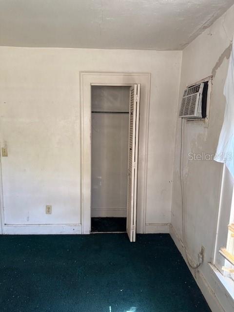 unfurnished bedroom with a closet and an AC wall unit