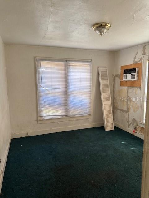 unfurnished room with plenty of natural light, a wall mounted AC, dark carpet, and baseboards