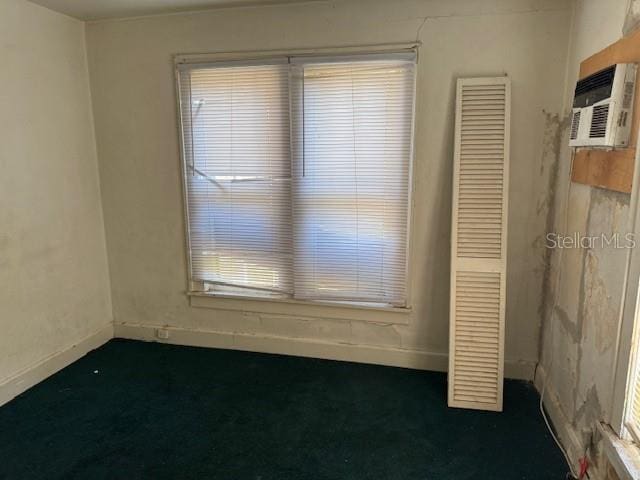 unfurnished room featuring a wall unit AC, carpet floors, and baseboards