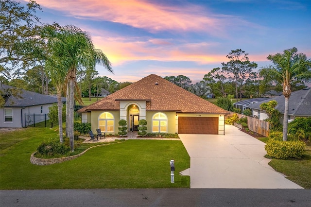 mediterranean / spanish home with an attached garage, a front yard, and fence