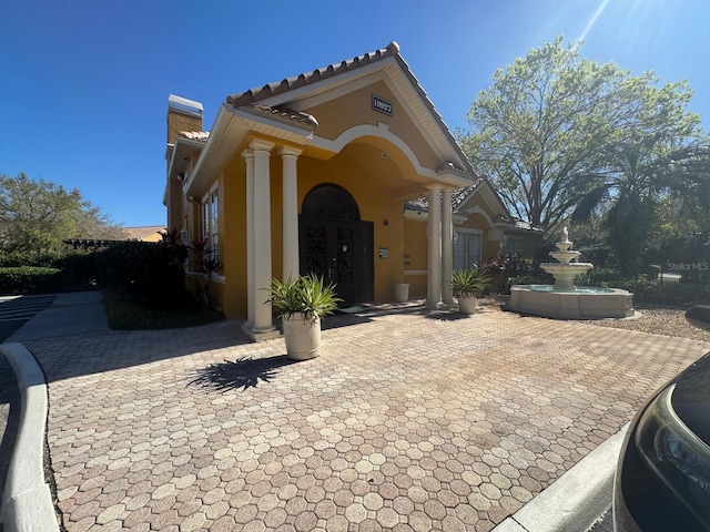 mediterranean / spanish-style home with a tiled roof, stucco siding, and french doors