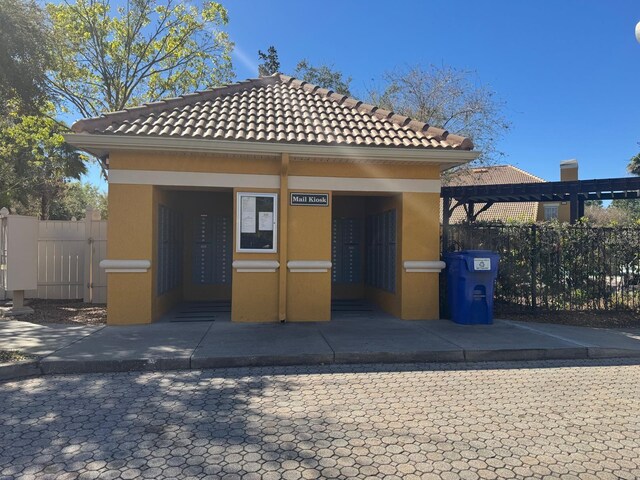 exterior space with stucco siding, a tiled roof, a pergola, and fence