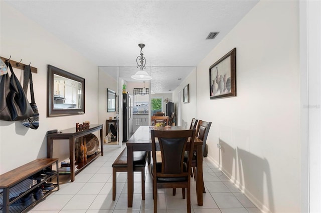 dining space featuring light tile patterned floors, baseboards, visible vents, and a textured ceiling