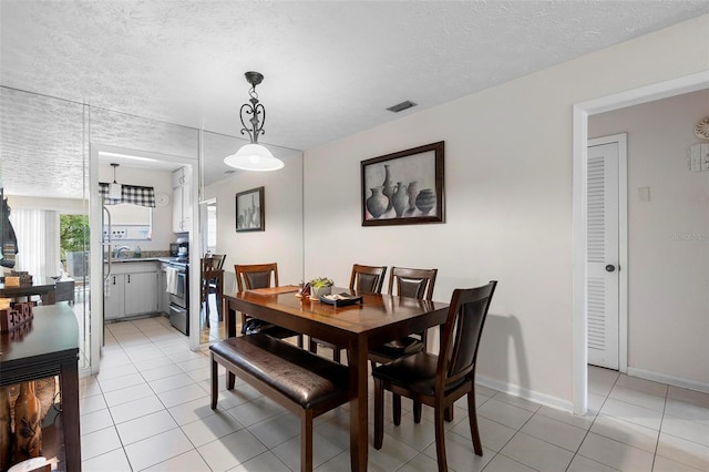 dining room with baseboards, visible vents, a textured ceiling, and light tile patterned flooring