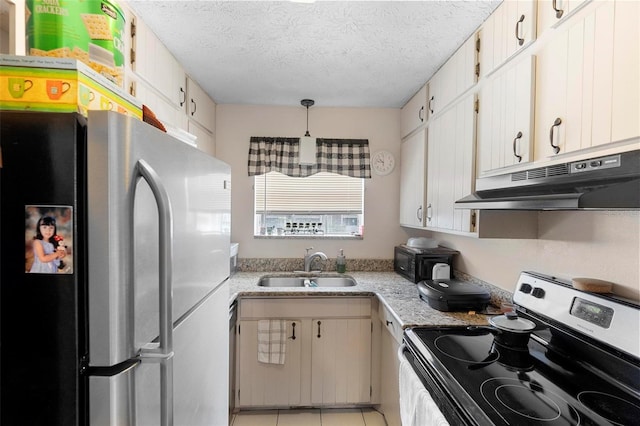 kitchen with appliances with stainless steel finishes, a textured ceiling, under cabinet range hood, a sink, and light tile patterned flooring