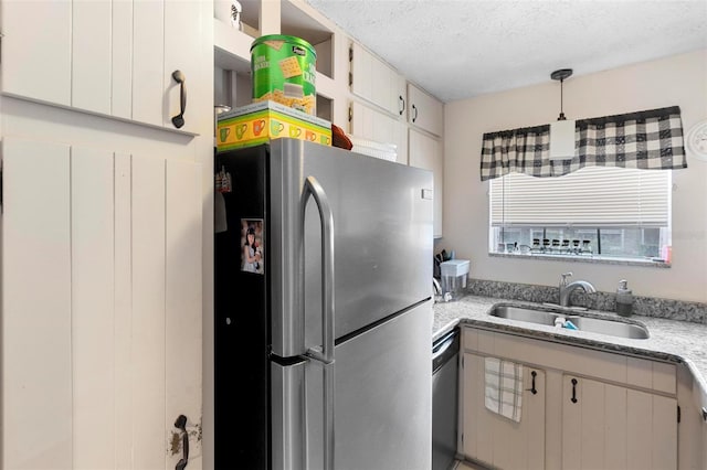 kitchen featuring light stone countertops, stainless steel appliances, a textured ceiling, pendant lighting, and a sink