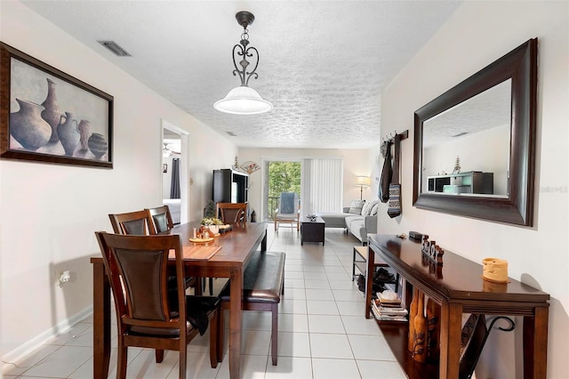 dining room featuring light tile patterned floors, baseboards, visible vents, and a textured ceiling