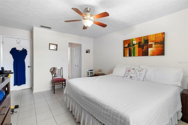 bedroom with light tile patterned floors, a ceiling fan, visible vents, and a textured ceiling