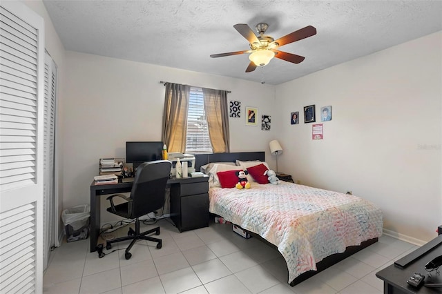 bedroom featuring baseboards, a ceiling fan, a textured ceiling, and light tile patterned flooring