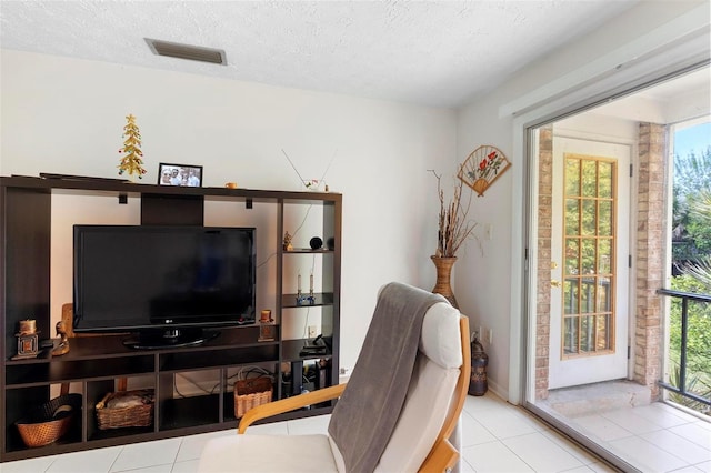 home office featuring a textured ceiling, tile patterned flooring, visible vents, and a healthy amount of sunlight