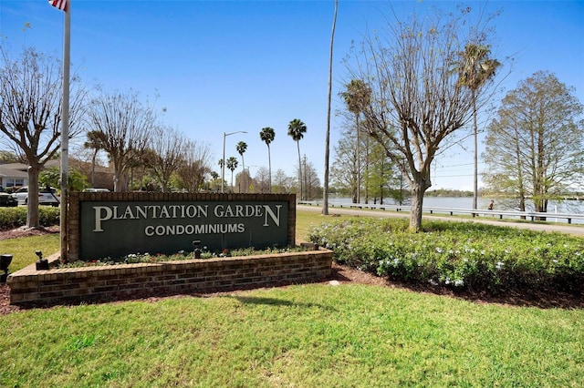 community sign with a lawn and a water view