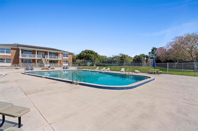 community pool with a yard, fence, and a patio