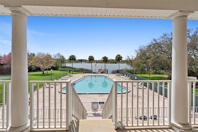 community pool featuring a water view, a patio area, and a yard