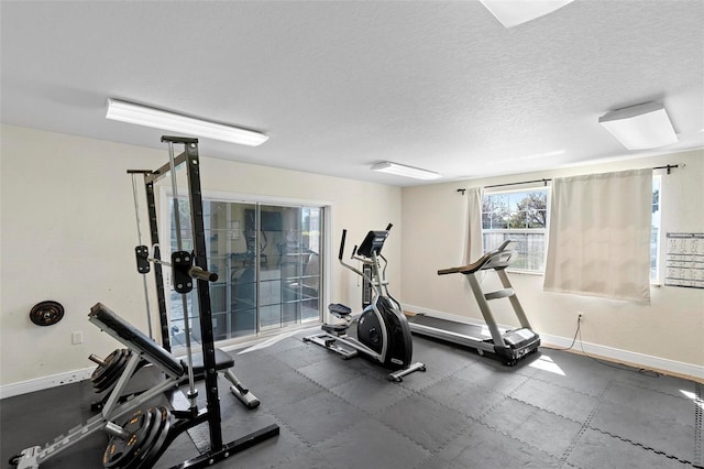 workout area featuring a textured ceiling and baseboards