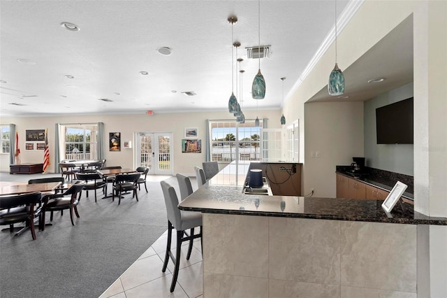 kitchen with french doors, pendant lighting, visible vents, ornamental molding, and dark stone counters