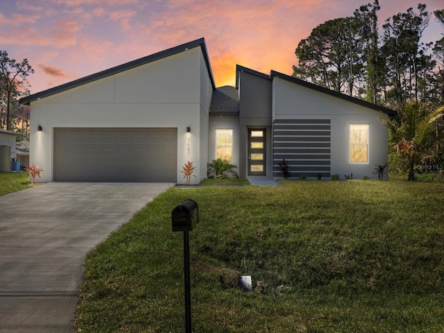 contemporary home featuring concrete driveway, a front yard, an attached garage, and stucco siding