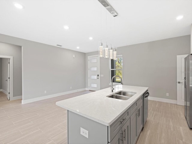 kitchen featuring light stone counters, gray cabinetry, a sink, baseboards, and stainless steel dishwasher