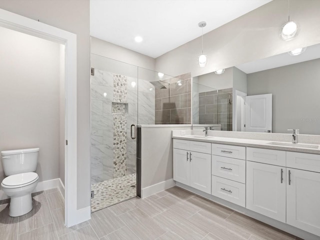 full bathroom with double vanity, toilet, a stall shower, a sink, and baseboards