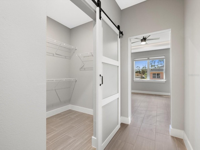 spacious closet with a barn door and wood finish floors