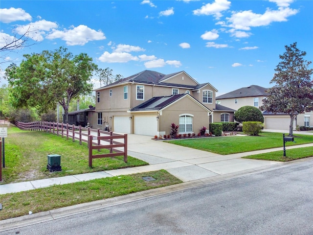 traditional home with stucco siding, an attached garage, fence, driveway, and a front lawn