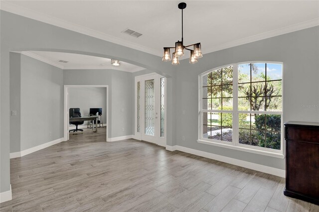 unfurnished dining area with baseboards, visible vents, arched walkways, light wood-style floors, and a chandelier