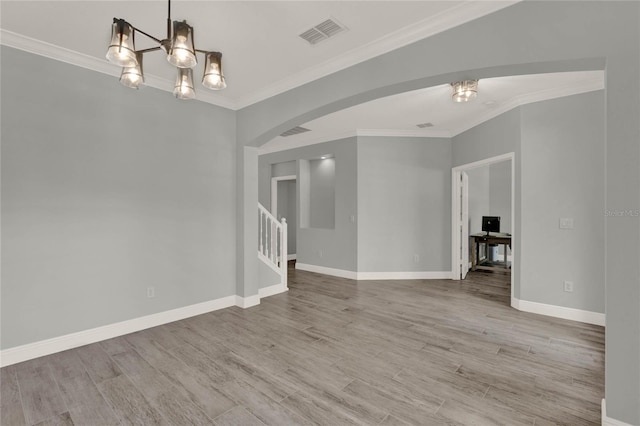 empty room with arched walkways, visible vents, crown molding, and wood finished floors