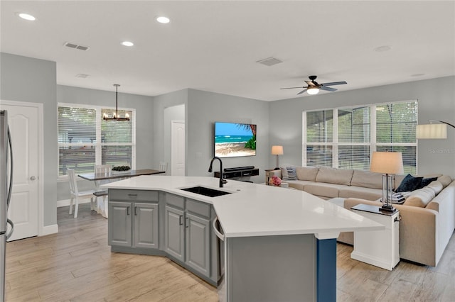 kitchen featuring visible vents, open floor plan, a sink, and gray cabinetry