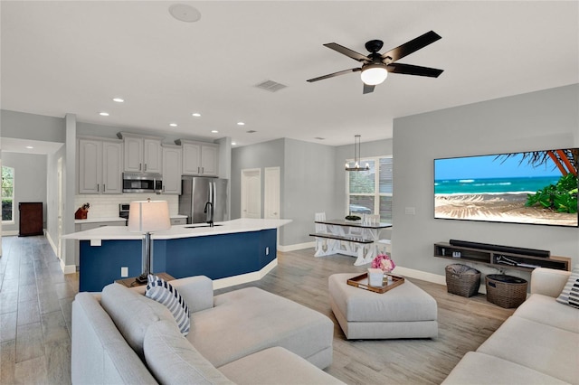 living room with light wood-style floors, baseboards, visible vents, and a wealth of natural light