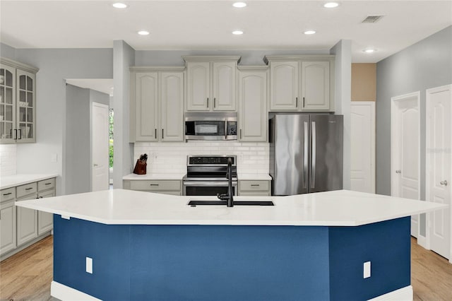 kitchen featuring light wood finished floors, visible vents, stainless steel appliances, and a sink