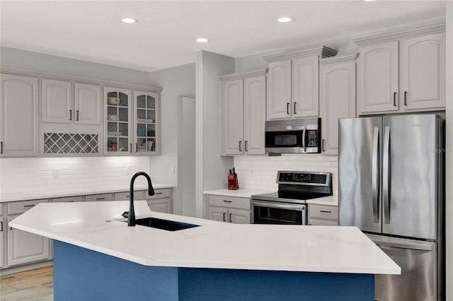 kitchen featuring a center island with sink, appliances with stainless steel finishes, light countertops, and a sink