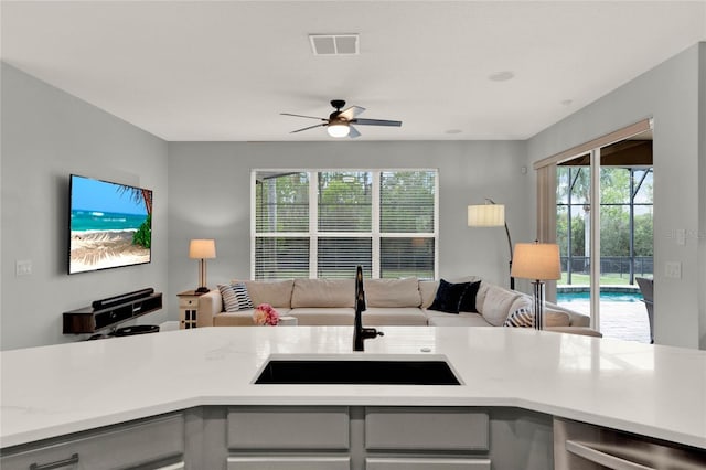 kitchen featuring light countertops, gray cabinets, a sink, and open floor plan