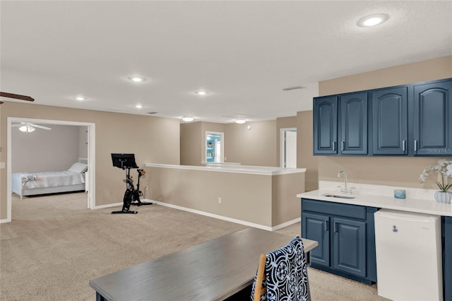 kitchen with dishwashing machine, light carpet, a sink, and blue cabinetry