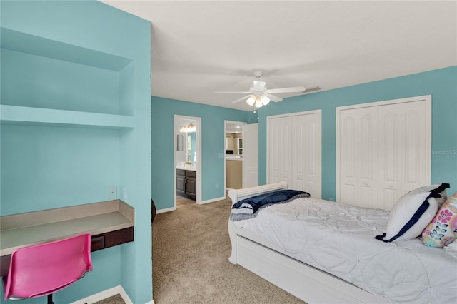 bedroom featuring baseboards, a ceiling fan, ensuite bathroom, carpet floors, and two closets