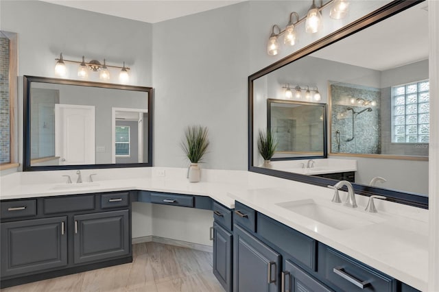 full bath with tiled shower, two vanities, and a sink